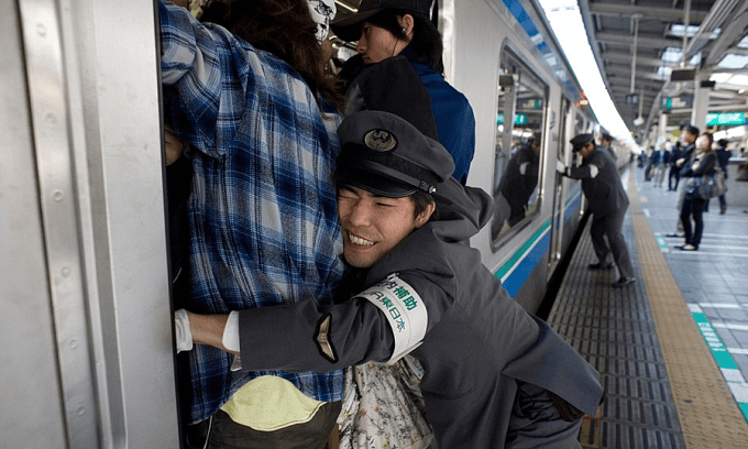 Một nhân viên hỗ trợ đẩy hành khách vào toa tàu ở Tokyo